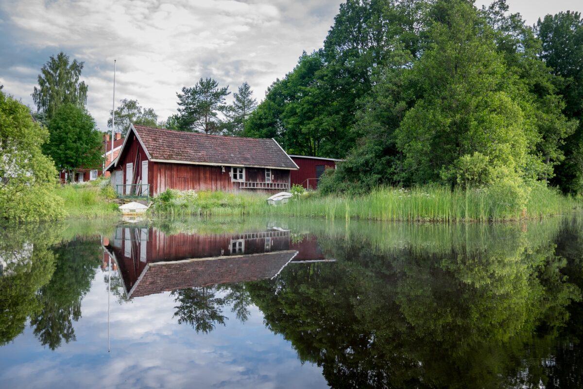En röd liten stuga vid en svensk sjö